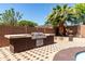 Outdoor kitchen with stainless steel grill and counter, set on a brick patio with a palm tree nearby at 18640 W Pioneer St, Goodyear, AZ 85338