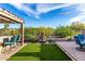 Serene backyard oasis featuring an outdoor kitchen, artificial grass, and a tranquil water feature at 21127 W Minnezona Ave, Buckeye, AZ 85396