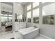 Bright bathroom featuring a soaking tub, dual sink vanity, tile floors, and natural light at 21127 W Minnezona Ave, Buckeye, AZ 85396