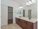 Bathroom featuring a double sink vanity, tile flooring, and closet access at 2845 N 104Th Ave, Avondale, AZ 85392