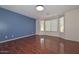 Bedroom with blue accent wall, hardwood floors, and large window at 2845 N 104Th Ave, Avondale, AZ 85392