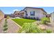 Landscaped backyard with lush plants, artificial turf, and a covered patio with a stucco home exterior at 31435 N 130Th Ave, Peoria, AZ 85383