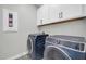 Modern laundry room with sleek appliances, white cabinets, and patterned tile flooring at 31435 N 130Th Ave, Peoria, AZ 85383