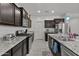 Well-equipped kitchen featuring granite countertops, stainless steel appliances, dark cabinets, and tile flooring at 37103 N El Morro Trl, San Tan Valley, AZ 85140