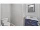 Updated half-bath with a navy vanity, modern fixtures, a framed mirror and a standard-height toilet at 396 S 166Th Dr, Goodyear, AZ 85338