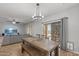 Stylish dining area with a rustic wooden table, modern chandelier, and sliding glass doors to the backyard at 396 S 166Th Dr, Goodyear, AZ 85338