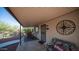 Covered back patio with outdoor seating, a decorative wall art, and a 'Be Happy' pillow on a floral bench at 612 N Signal Butte Rd, Mesa, AZ 85207
