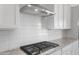 Detailed view of a modern gas cooktop with a sleek stainless steel vent hood and bright subway tile backsplash at 662 W Rock Needle Trl, Apache Junction, AZ 85120