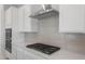 Close up of cooktop and cabinets, modern range hood, quartz counters, and tiled backsplash at 674 W Rock Needle Trl, Apache Junction, AZ 85120