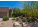 Charming single-story home featuring desert landscaping, rocks, and mature trees in the front yard at 6855 E Amber Sun Dr, Scottsdale, AZ 85266