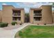 Apartment building with private patios, covered terraces, and manicured grounds including grassy areas and mature landscaping at 8260 E Arabian Trl # 257, Scottsdale, AZ 85258