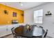 Bright dining room with a dark wood table, white walls, yellow accent wall, and plenty of seating at 9916 E Texas Ave, Mesa, AZ 85212