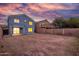 Expansive backyard featuring a home with a covered patio and well-lit windows against a colorful sunset sky at 10831 E Azalea Ave, Mesa, AZ 85208