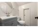 A modern half bathroom with a round mirror and contemporary vanity with gray cabinets at 10831 E Azalea Ave, Mesa, AZ 85208
