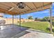 Covered patio with ceiling fan overlooks expansive backyard featuring lush grass and mature landscaping at 12605 W Dreyfus Dr, El Mirage, AZ 85335
