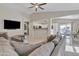 View of the living room with a TV, gray sectional, and open access to the kitchen and dining area at 12605 W Dreyfus Dr, El Mirage, AZ 85335