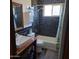 This bathroom features dark tiling, a tub and shower combination, and a wood and metal accented sink and storage at 12607 N 23Rd St, Phoenix, AZ 85022