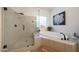 Serene bathroom featuring a glass-enclosed shower and luxurious soaking tub by a window at 13458 W Coronado Rd, Goodyear, AZ 85395