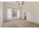 Spacious main bedroom with neutral carpet, ceiling fan, large window, and access to the ensuite bathroom at 1424 W Mead Dr, Chandler, AZ 85248