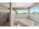 Luxurious bathroom features a large soaking tub, a glass-enclosed shower, and ample natural light at 1435 E Rancho Dr, Phoenix, AZ 85014