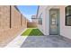 Side yard with artificial turf, brick wall, stone pavers and a glass door at 20308 W Roma Ave, Buckeye, AZ 85396