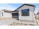 Charming home featuring white siding, a dark gray garage door and meticulous landscaping at 20308 W Roma Ave, Buckeye, AZ 85396