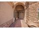 Inviting entryway featuring a charming stone archway and a decorative wooden door at 20740 N 62Nd Ave, Glendale, AZ 85308