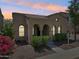 Inviting home with a charming facade, arched windows, desert landscaping, and warm exterior lighting at 21155 W Green St, Buckeye, AZ 85396