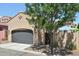 Attractive desert home boasts a gray garage door, desert landscaping, and a mature tree providing shade at 21155 W Green St, Buckeye, AZ 85396