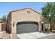 The gray garage door of this home is accented by desert landscaping, architectural details, and ambient lighting at 21155 W Green St, Buckeye, AZ 85396