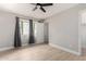 A neutral bedroom featuring a ceiling fan and large windows with grey curtains at 2502 N 22Nd Dr, Phoenix, AZ 85009