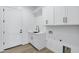 Bright laundry room with white cabinetry, sink, and modern fixtures at 26643 S 169Th Pl, Queen Creek, AZ 85142
