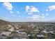 An aerial view showcasing neighborhood homes nestled amongst rolling hills, under a blue sky with fluffy clouds at 27 W Cochise Dr, Phoenix, AZ 85021