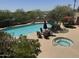 Community pool and hot tub are surrounded by greenery and patio furniture at 27 W Cochise Dr, Phoenix, AZ 85021