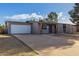 Single story grey home with front lawn and long driveway to attached garage at 3021 E Larkspur Dr, Phoenix, AZ 85032