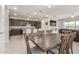 Open-concept dining area flowing into a modern kitchen with dark cabinetry and a central island at 686 N 152Nd Dr, Goodyear, AZ 85338