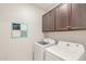 Bright laundry room with upper cabinets and modern appliances, including a washer and dryer at 686 N 152Nd Dr, Goodyear, AZ 85338