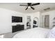 Bright main bedroom featuring ceiling fan, ensuite bathroom, dresser with tv, and large mirror at 7028 W Lincoln St, Peoria, AZ 85345