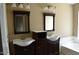 Bathroom featuring dual sinks with dark wood cabinets and framed mirrors at 7240 W Los Gatos Dr, Glendale, AZ 85310
