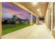 An inviting covered patio with outdoor seating overlooks a lush lawn and landscaped garden at twilight at 7848 E Parkview Ln, Scottsdale, AZ 85255