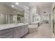 Bright bathroom featuring dual sinks, a soaking tub, and a large walk-in closet with mirrored doors at 7848 E Parkview Ln, Scottsdale, AZ 85255