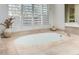 Close up of tiled, oval-shaped bathtub beneath a window with white shutters at 7848 E Parkview Ln, Scottsdale, AZ 85255