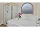 Bright bathroom features a soaking tub, glass-enclosed shower, and decorative window at 8531 E Natal Cir, Mesa, AZ 85209