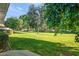 This backyard features a sprawling green lawn dotted with mature shade trees and lush landscaping at 9613 W Shasta Dr, Sun City, AZ 85351