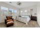 Bright bedroom featuring a distressed white wood bed frame, leather chair, and multiple windows at 10220 E Thatcher Ave, Mesa, AZ 85212