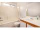Bright bathroom with white tile and fixtures, a shower-tub combo, and a spacious vanity area at 12132 W Dahlia Dr, El Mirage, AZ 85335