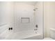 Crisp white tiled shower and bath with shower niche and black hardware at 122 W Cottage Ln, Tempe, AZ 85282