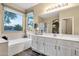 Bright bathroom featuring a soaking tub under a large window, vanity with double sinks and a walk-in shower at 20848 E Desert Hills Blvd, Queen Creek, AZ 85142