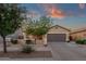 Charming single-story home with manicured front yard and two-car garage under a colorful dusk sky at 20848 E Desert Hills Blvd, Queen Creek, AZ 85142