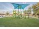 Community playground featuring covered play equipment, slides, and climbing structures on a well-maintained lawn at 26232 N 121St Ln, Peoria, AZ 85383